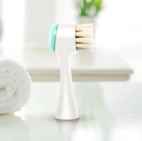 A double-sided facial brush with extra long bristles and a small silicone disc on one side
