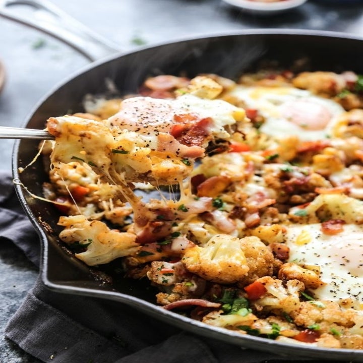 Taking a scoop of egg and cauliflower hash from a skillet.