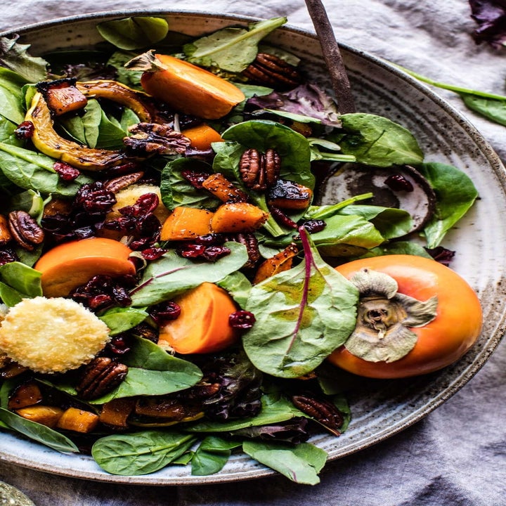 Spinach salad with cranberries, butternut squash, goat cheese, and a persimmon.