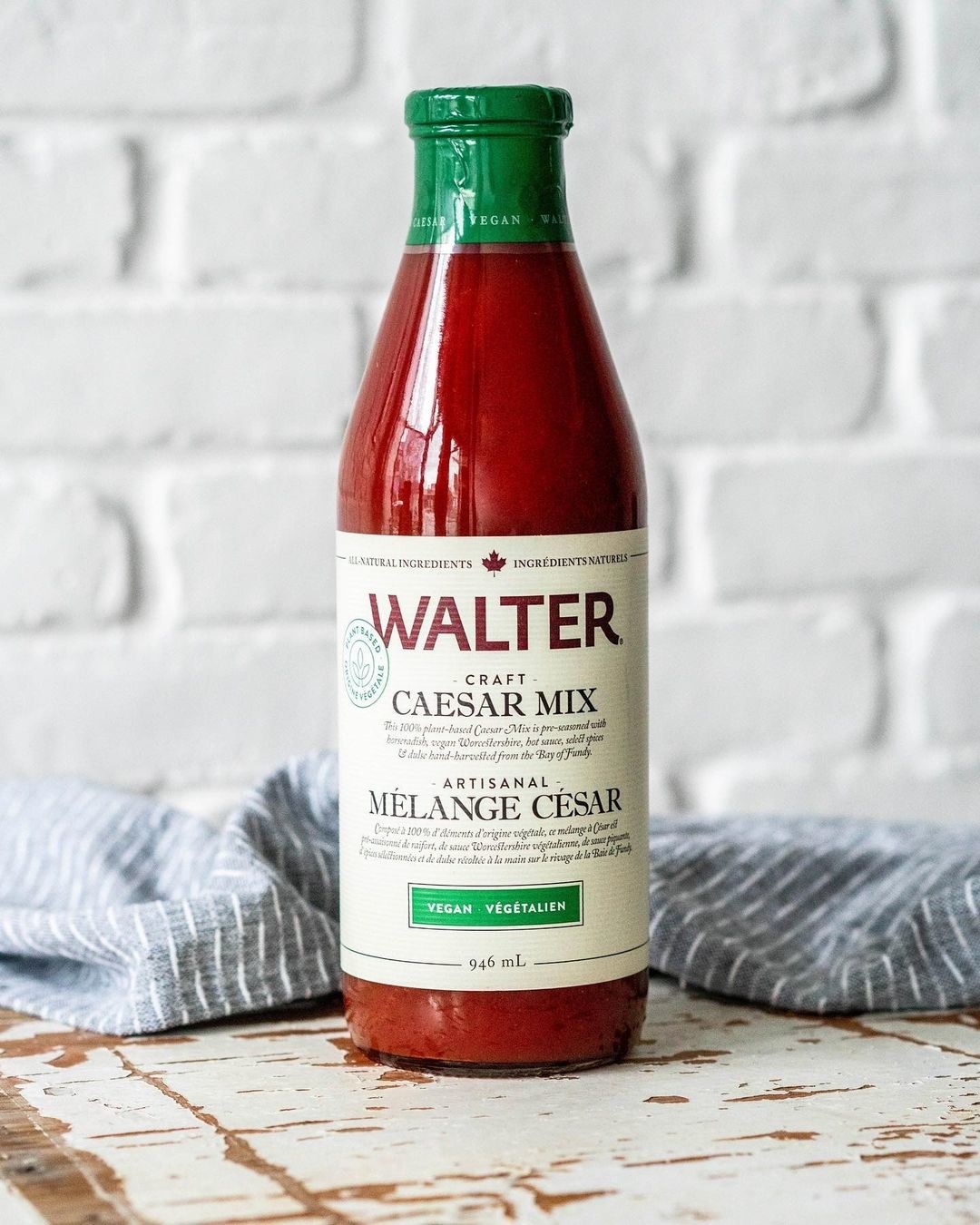 A bottle of vegan Caesar mix on a rustic counter