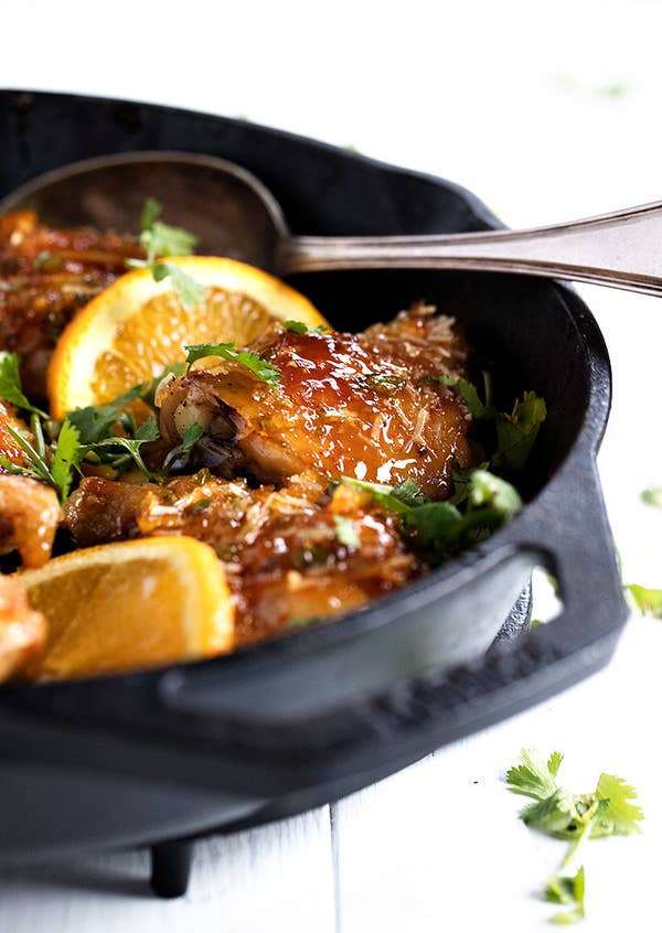 A skillet of sticky orange chicken thighs.