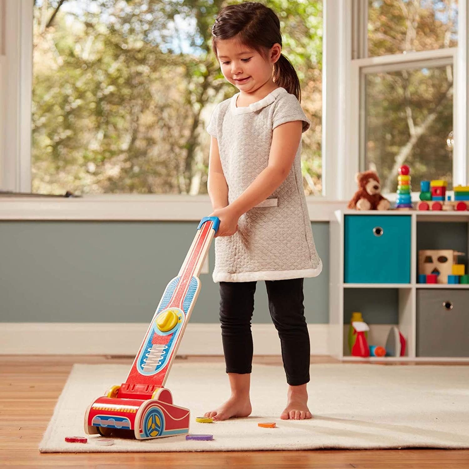 child using the toy vacuum to pick up some pieces