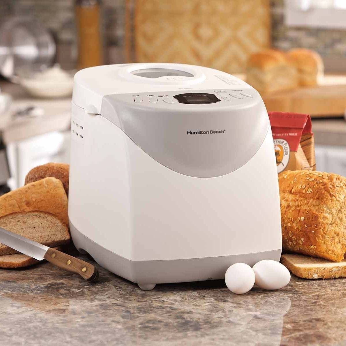 The white bread maker surrounded by delicious loaves
