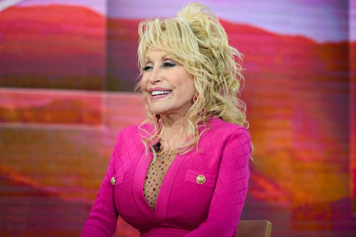 Dolly Parton wears a dress with buttons as she smiles at NBC Studios