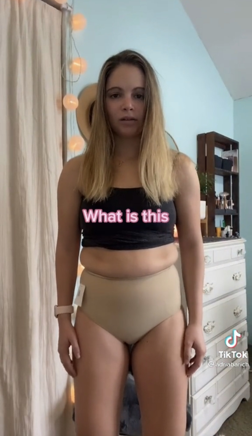 Adria wearing the shapewear with the caption: What is this