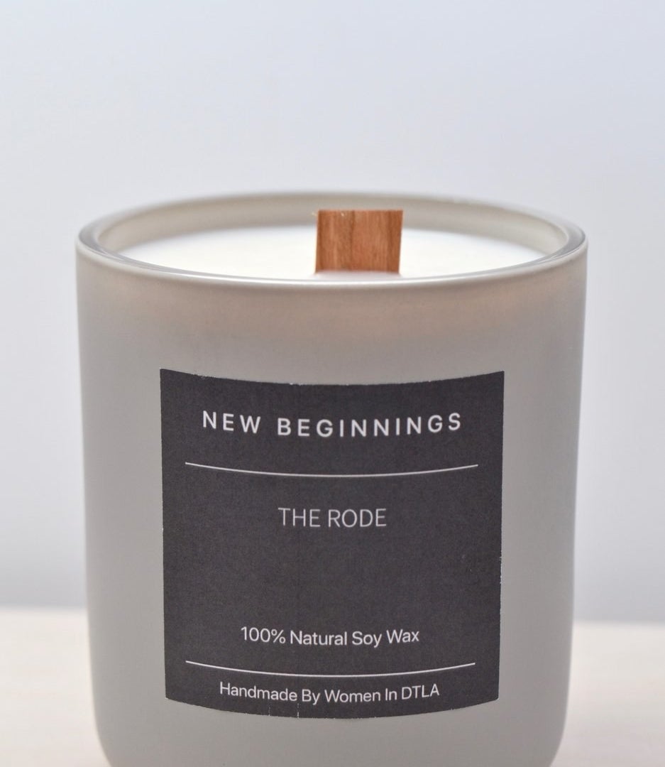 a candle with a wood wick and a label that says &quot;new beginnings&quot;