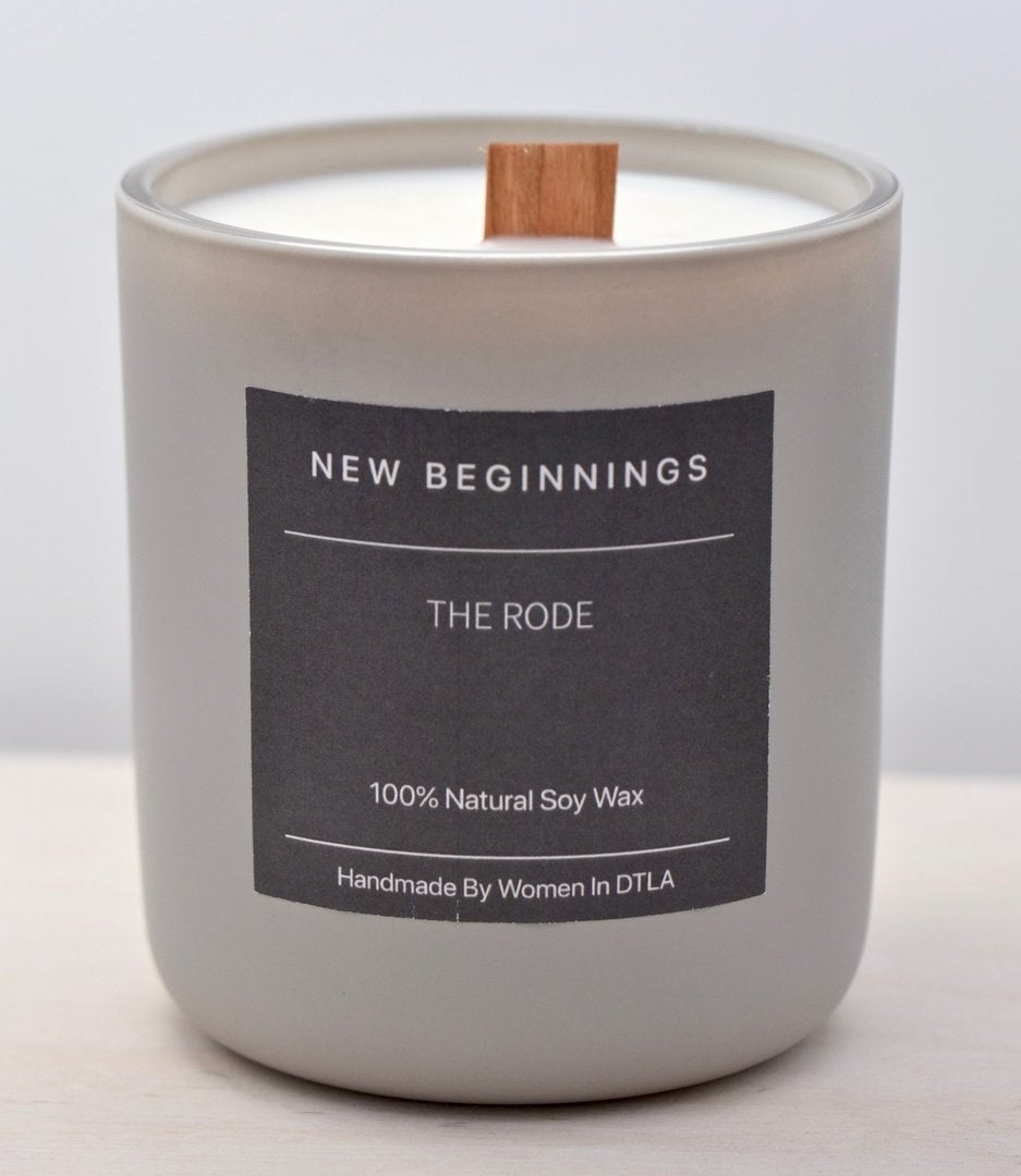 a candle with a wood wick and a label that says "new beginnings"