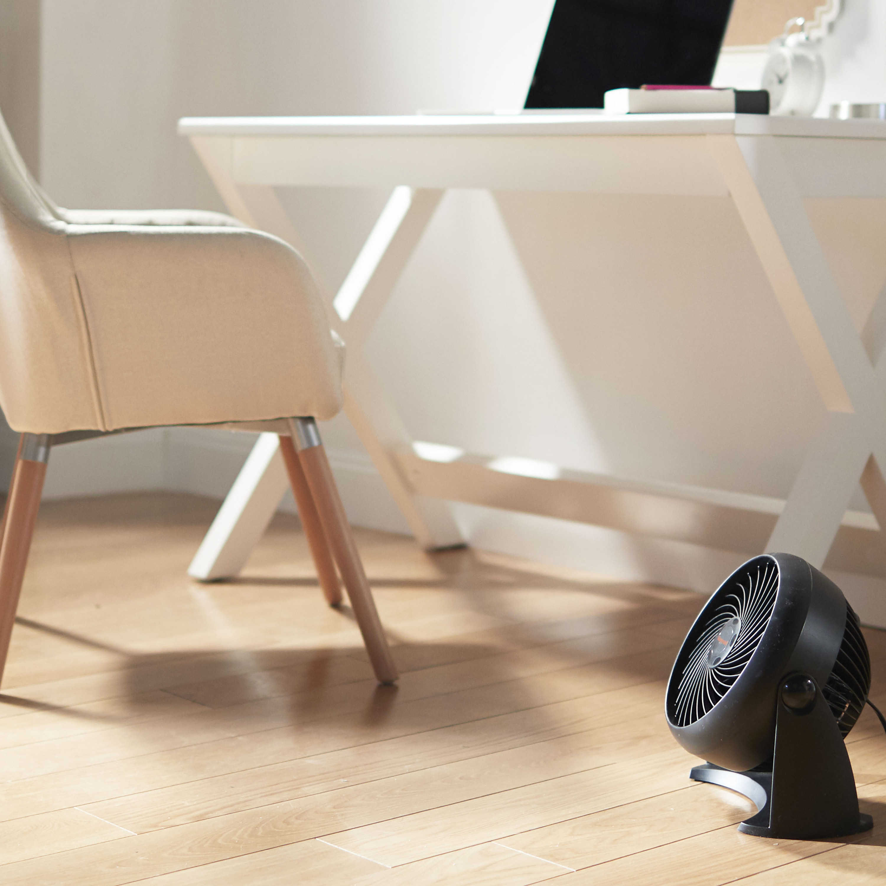 The black fan in a home office setting with white furniture