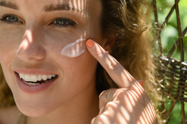 woman putting sunscreen on her face