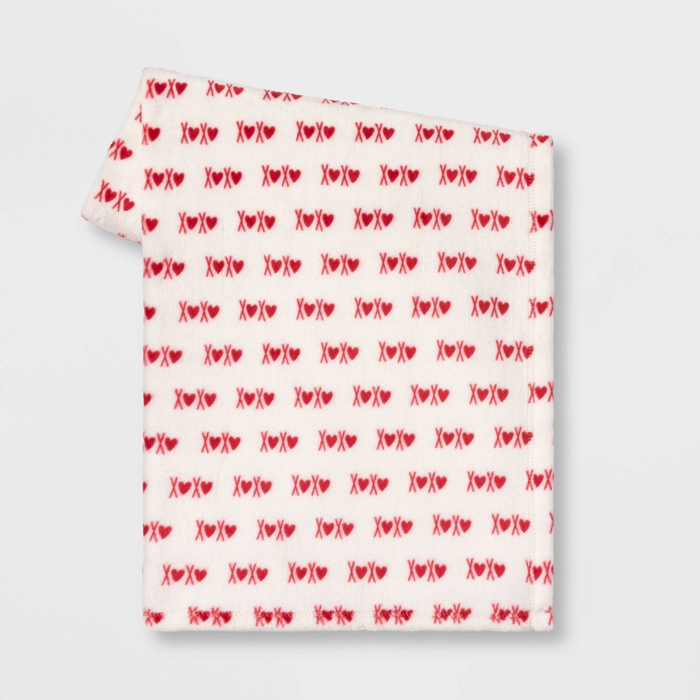 The blanket, which is white, with &quot;xoxo&quot; printed in red, with the &quot;o&quot;s replaced with hearts