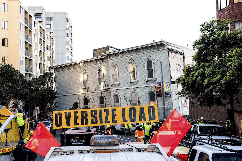 Sign reading &quot;Oversize Load&quot; in front of house on wheels