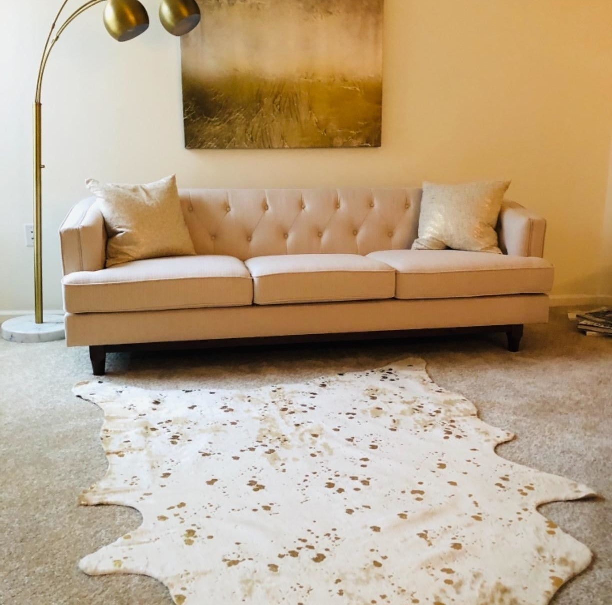 reviewer image of the faux cowhide rug in a blob-like shape in a living room
