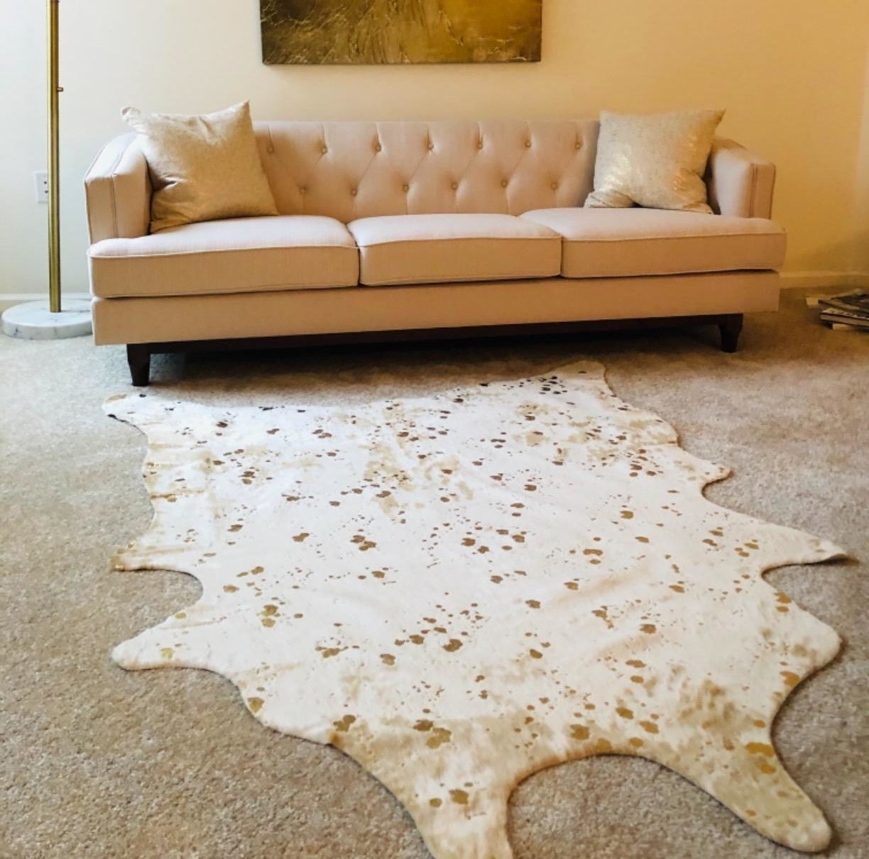 reviewer image of the faux cowhide rug in a blob-like shape in a living room