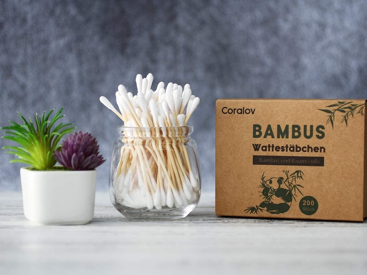 A jar of bamboo cotton swabs next to the carton they arrive in