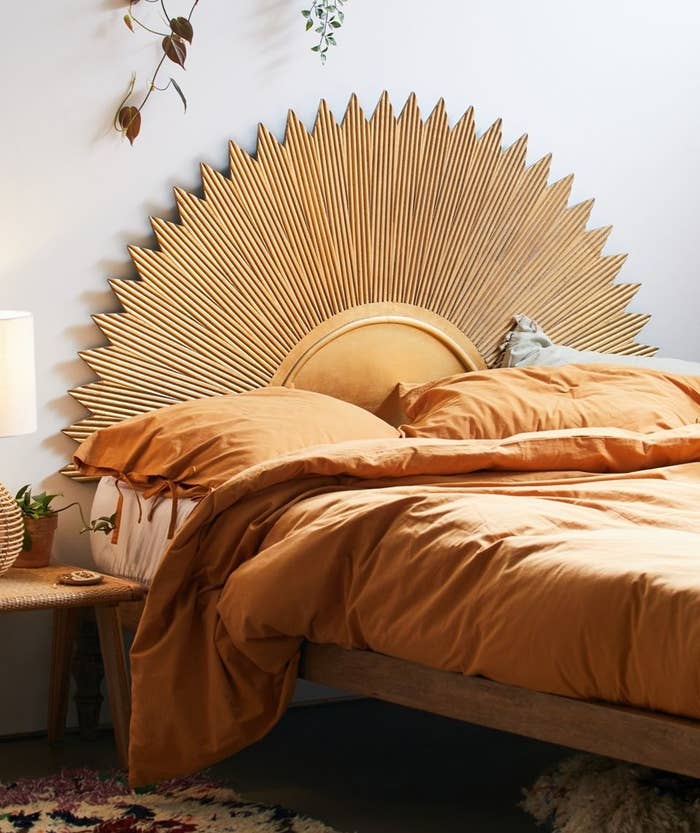 the half-circle-shaped gold headboard that looks like a sun above a bed