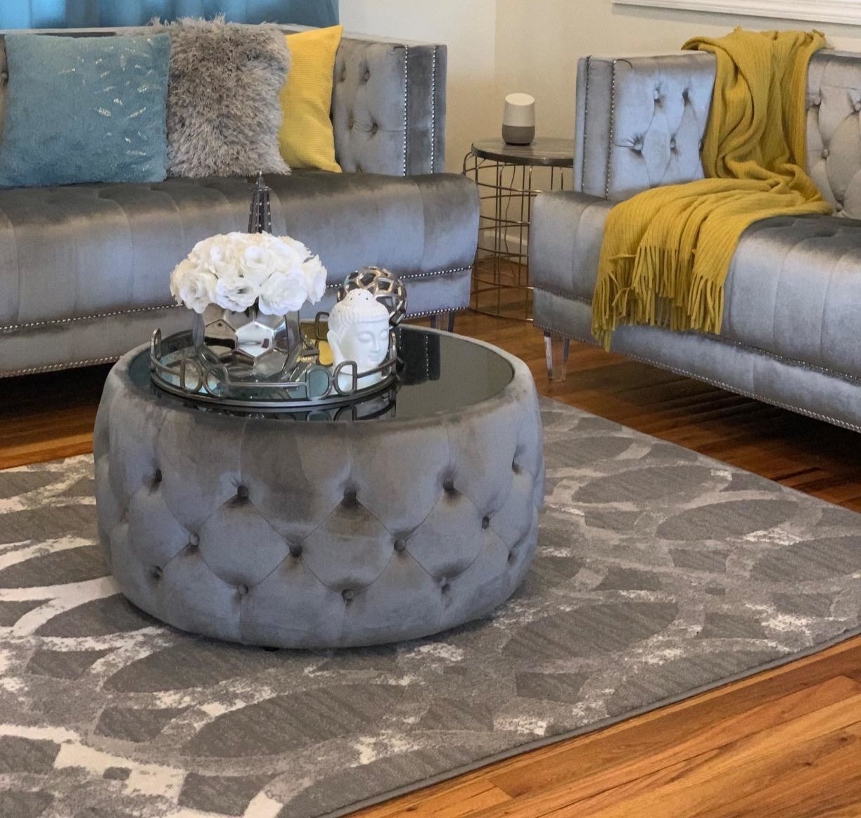 reviewer image of the large round tufted velvet grey ottoman with black glass top