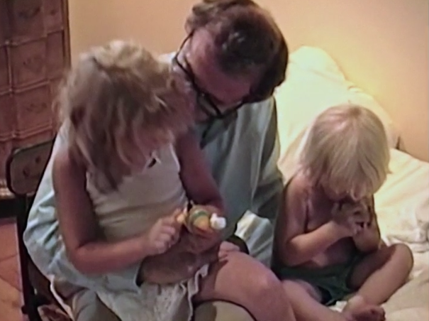 Dylan sitting on Woody's lap as Ronan sits off to the side on the bed