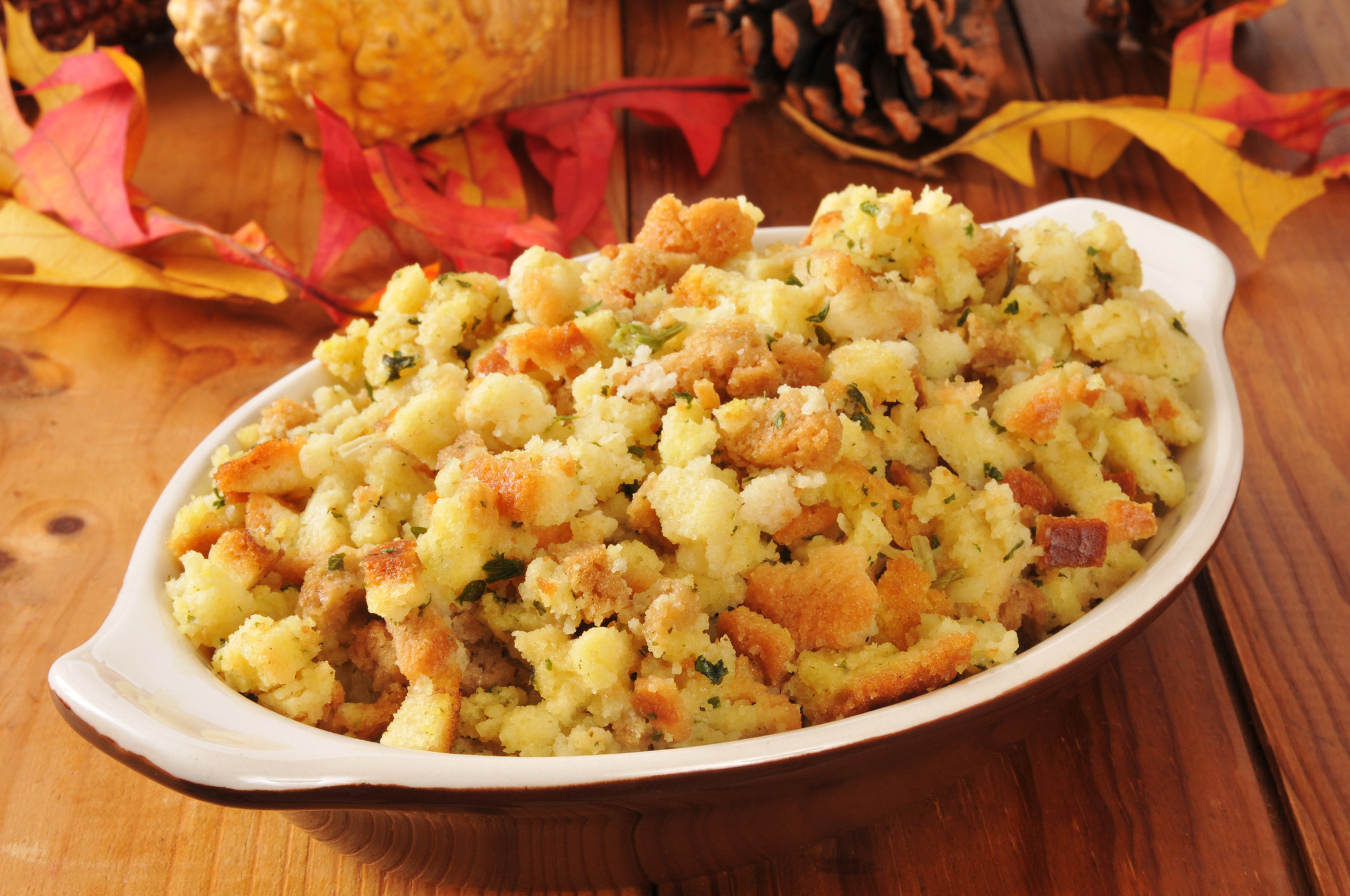 A small casserole dish of cornbread stuffing on a rustic wooden table.