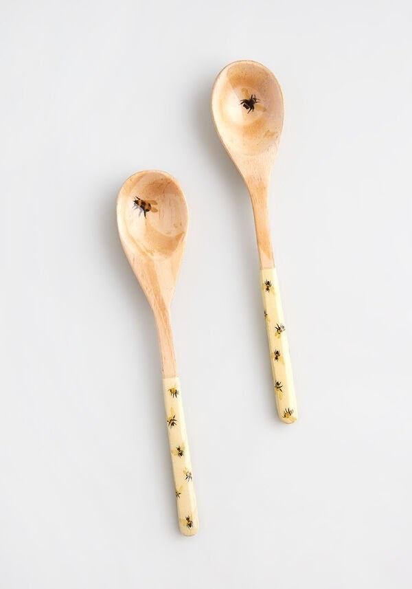 two wooden spoons with small painted bees on the handle and in the center of the spoons