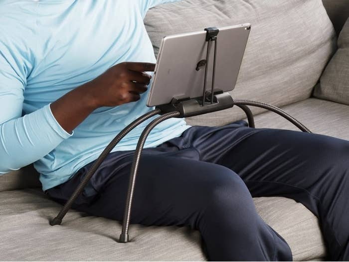 the black tablet holder with four legs over a model&#x27;s legs, showing how it holds the tablet easily