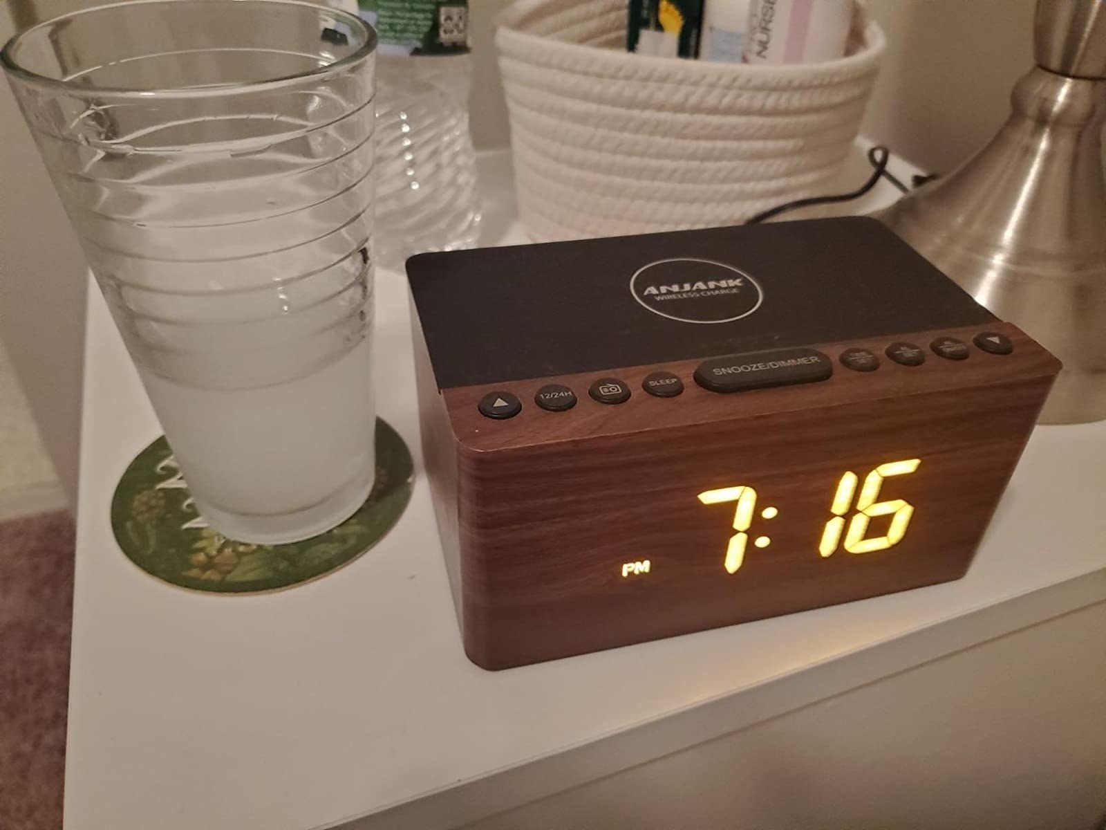 reviewer image of the anjank wooden digital alarm clock on a bedside table reading the time 7:16 PM