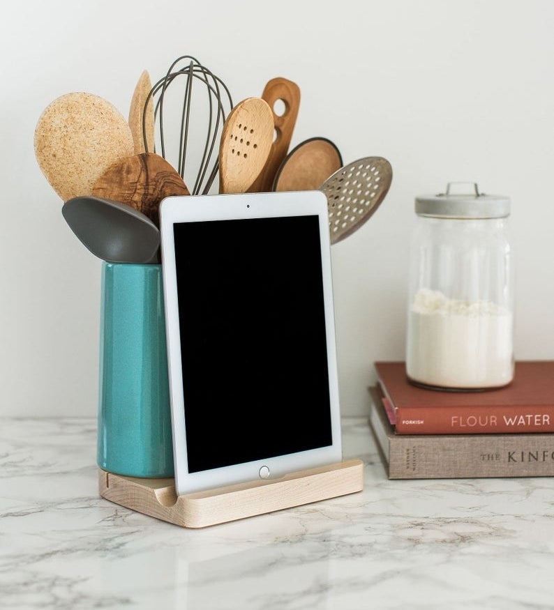 wood base tablet dock and green ceramic holder with kitchen utensils in it