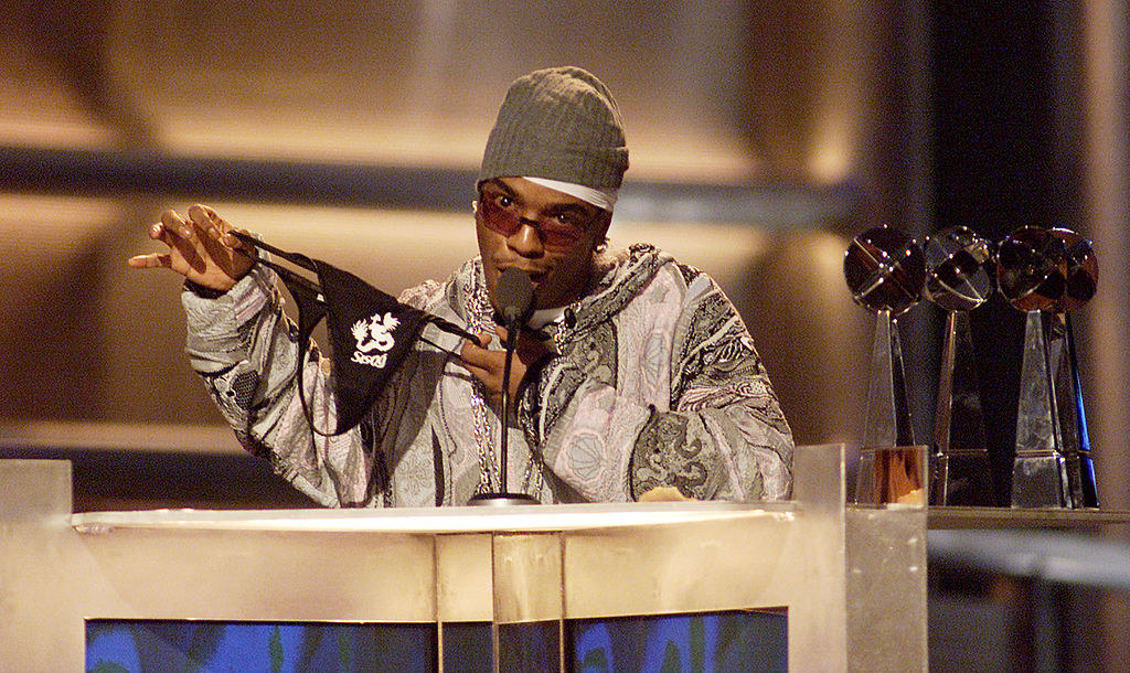 Sisqó onstage at an awards show and holding up a thong with his name on it 