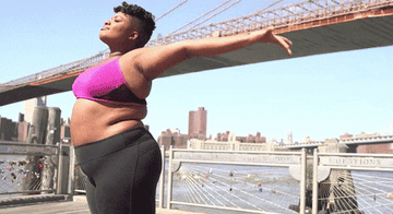 GIF of a plus-size woman smiling while stretching outdoors