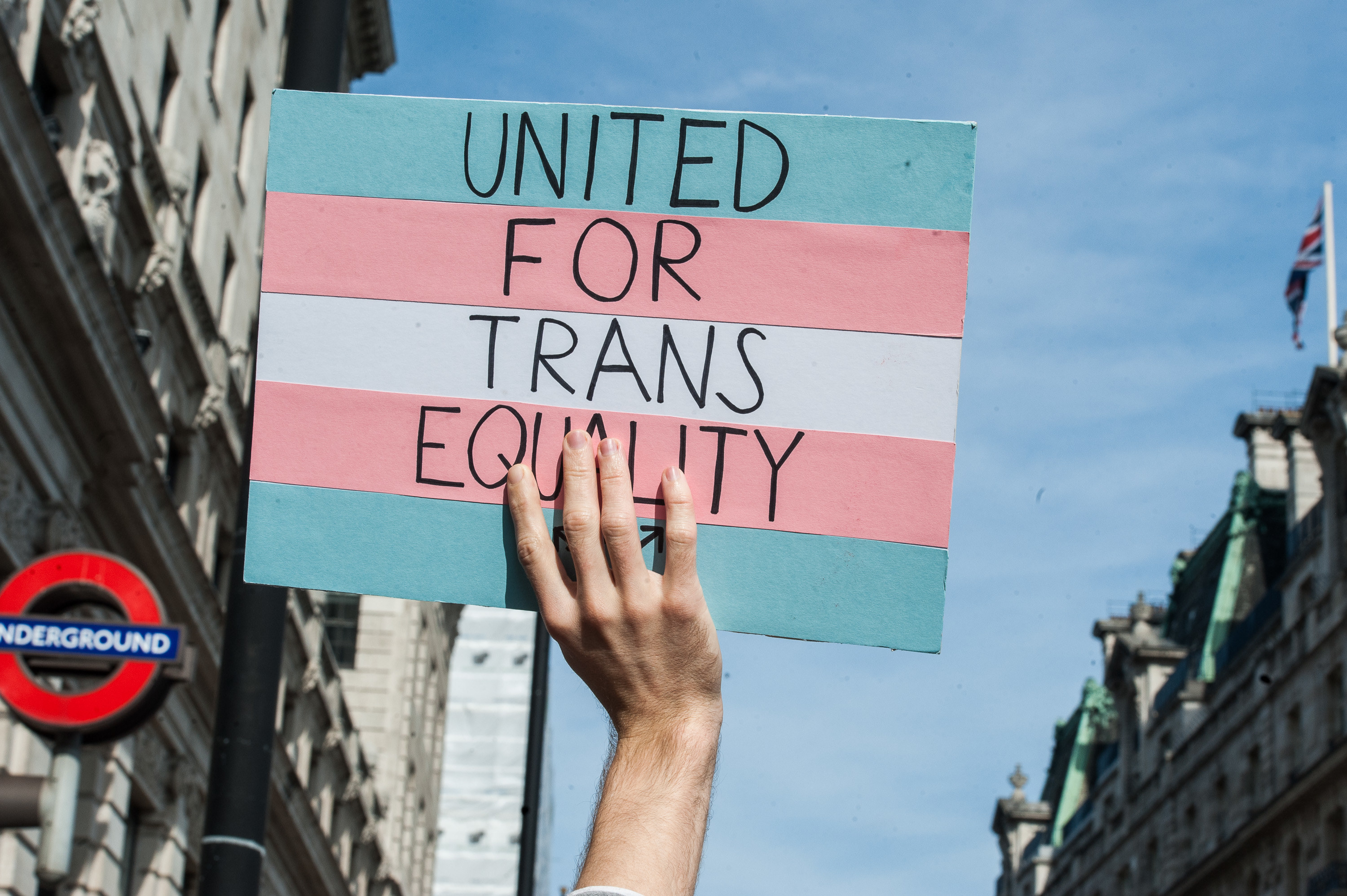 An image of a hand holding up a sign that says, &quot;United for trans equality&quot;
