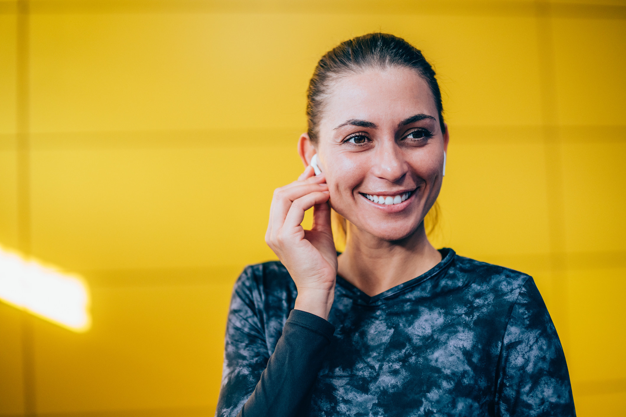 A woman smiling and putting her AirPod in