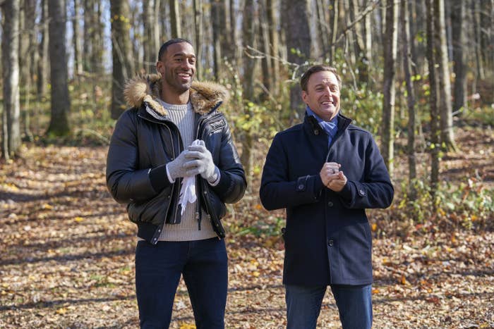 Matt James and Chris Harrison stand next to each other in the woods in an episode of The Bachelor