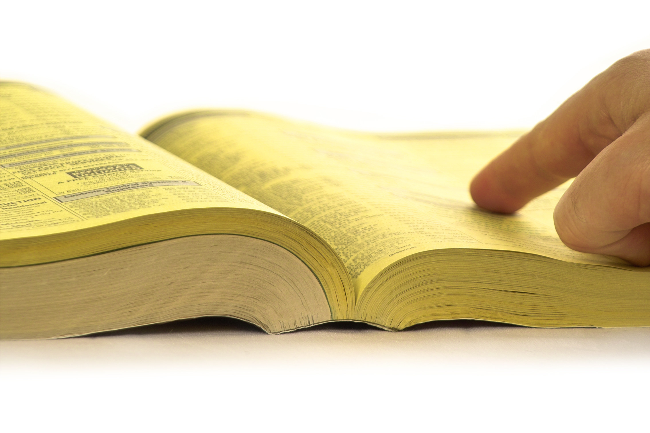 A open yellow book with a finger pointing towards a number