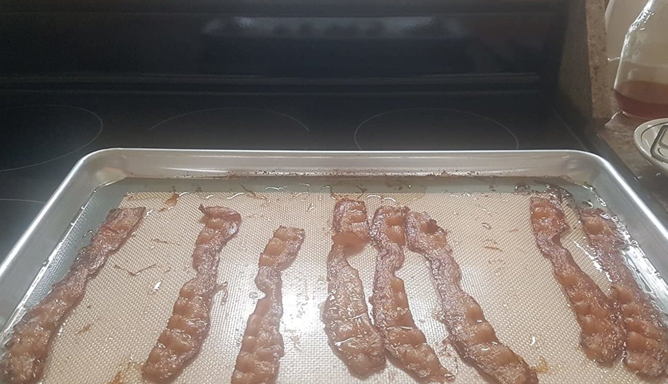 reviewer photo showing a baking sheet with the baking mat applied and crispy bacon laying across it