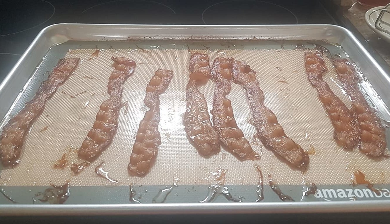 reviewer photo showing a baking sheet with the baking mat applied and crispy bacon laying across it