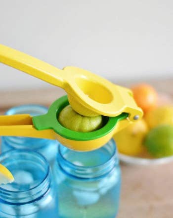 a yellow and green lemon and lime squeezer pressing a lime over glasses of water