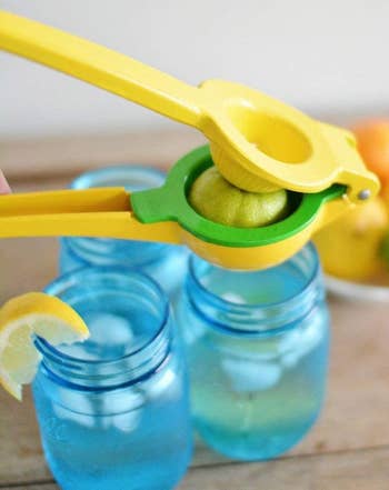 a yellow and green lemon and lime squeezer pressing a lime over glasses of water
