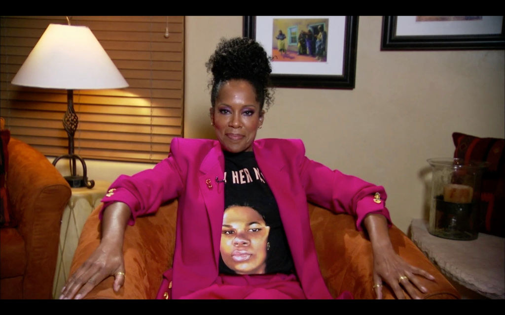Regina King sitting in a chair at the 72nd Emmy Awards, wearing a &quot;Say Her Name&quot; Breonna Taylor shirt