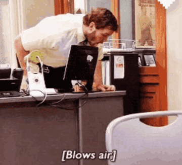 Chris Pratt blowing air on a computer in parks and rec 