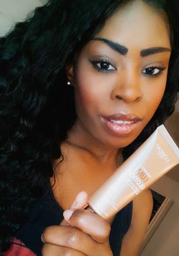 Reviewer wearing and holding L'Oreal Paris Makeup True Match Lumi Glotion