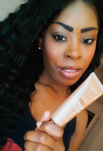 Reviewer wearing and holding L'Oreal Paris Makeup True Match Lumi Glotion