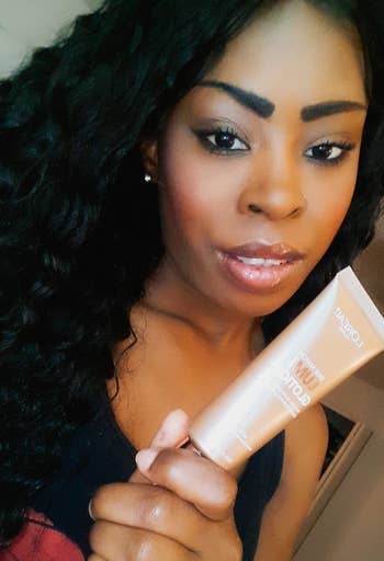 Reviewer wearing and holding L'Oreal Paris Makeup True Match Lumi Glotion