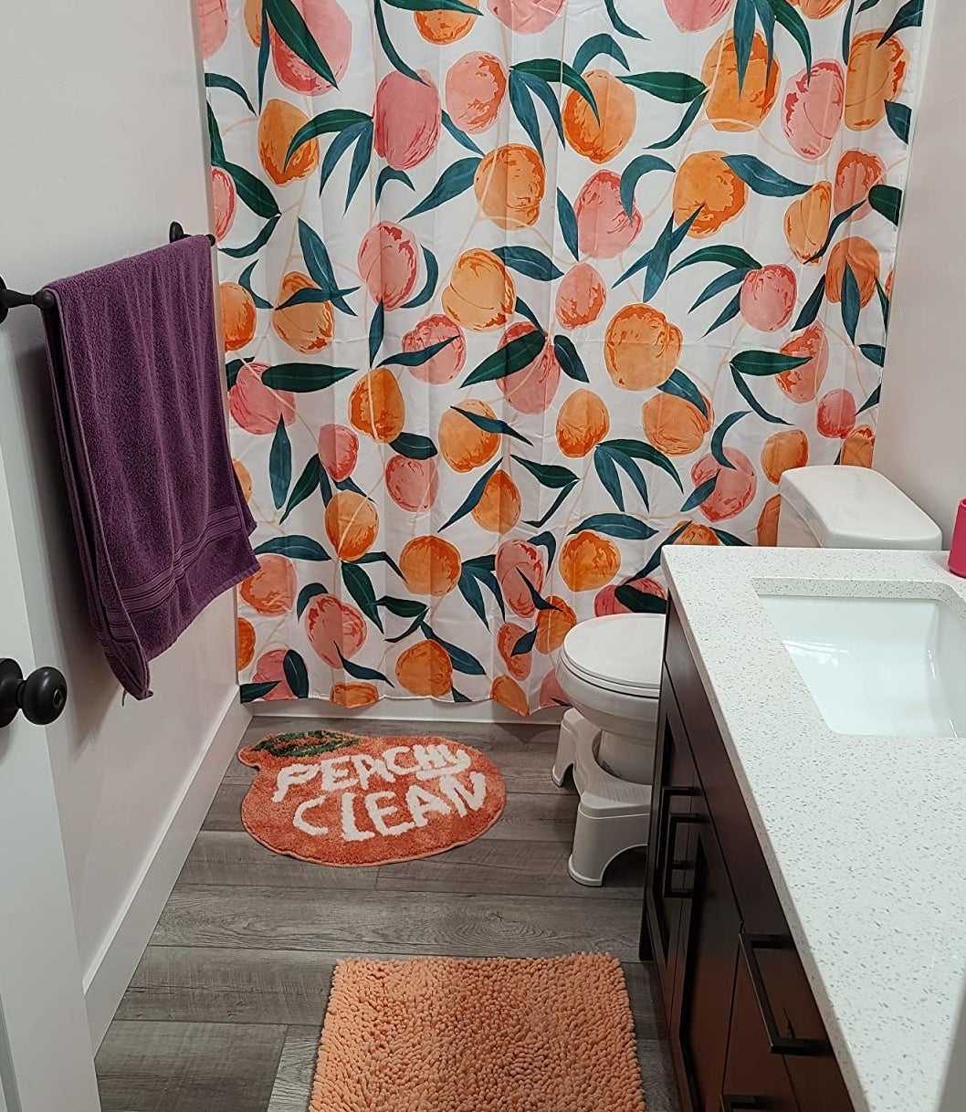 reviewer image of the white shower curtain with peach and orange illustrations of peaches with green leaves