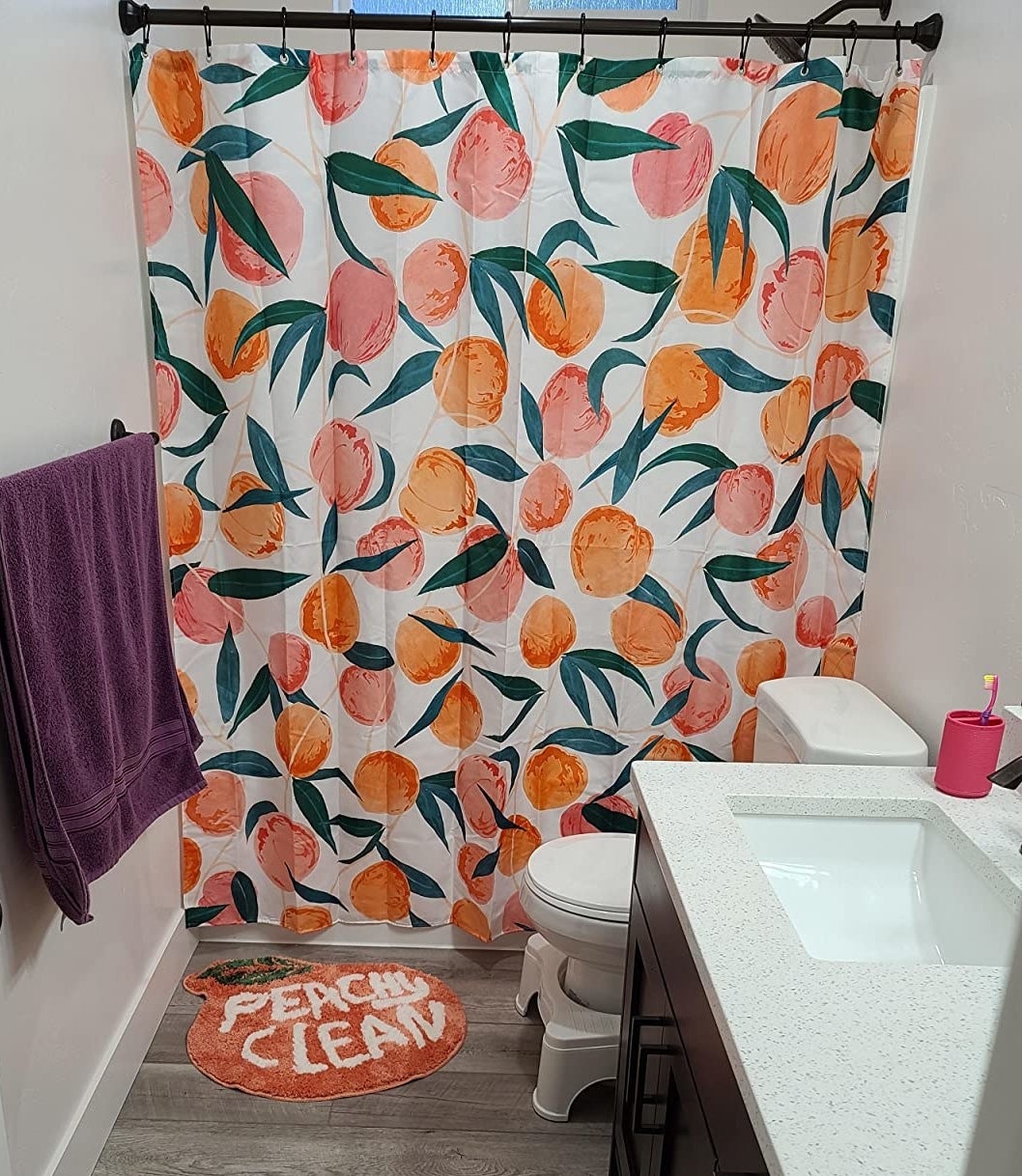reviewer image of the white shower curtain with peach and orange illustrations of peaches with green leaves