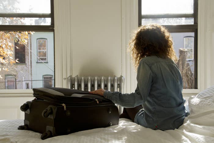 person sitting on a bed with their suitcase