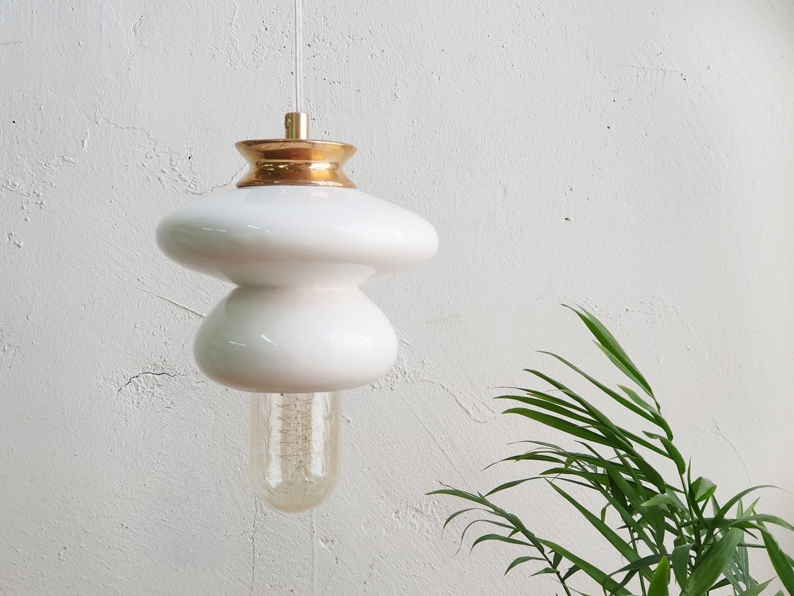 the pendant light with white round ceramic design in two different sizes and a gold end connecting it to the wire