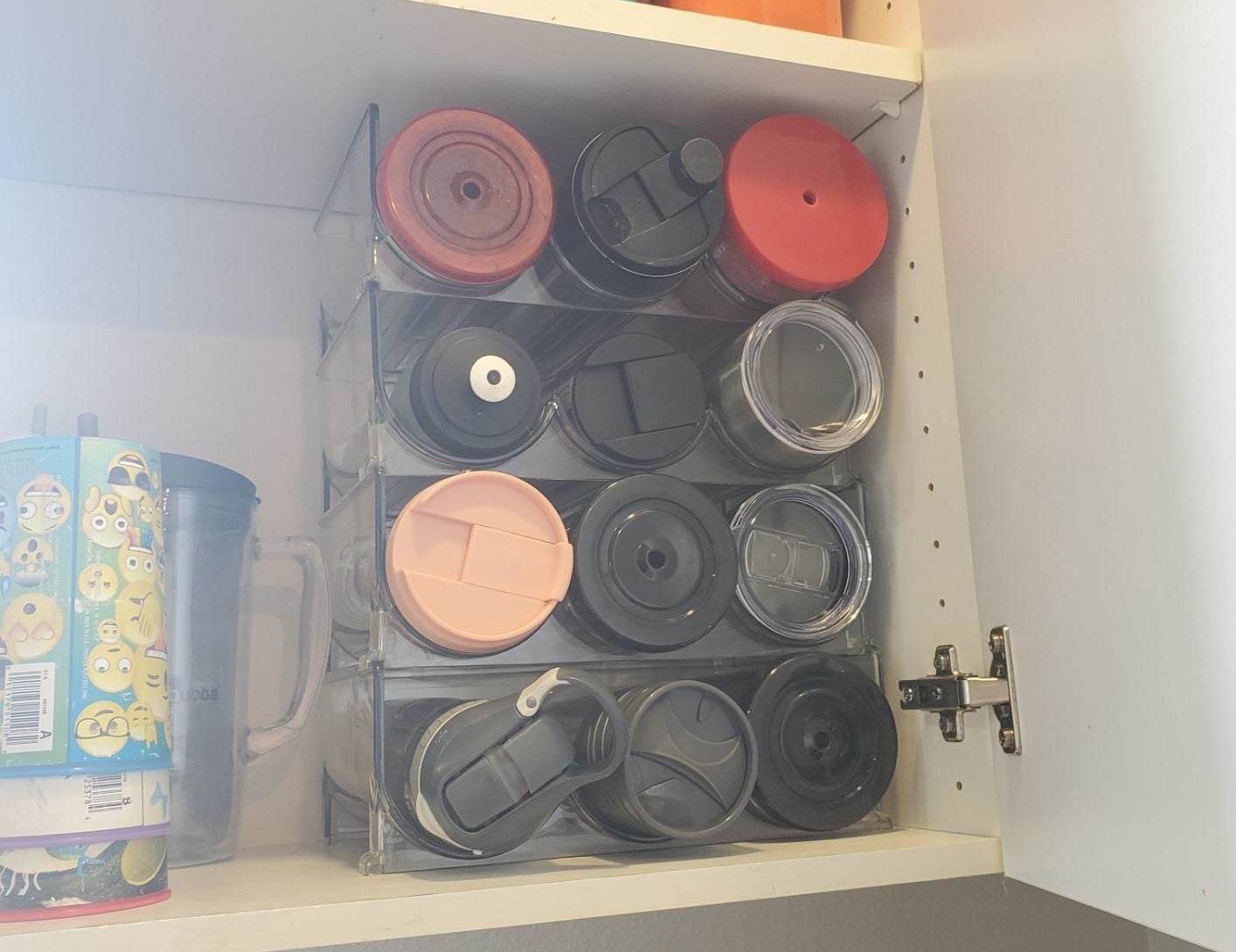 reviewer photo showing their water bottles and tumblers perfectly organized, maximizing space in their cupboards with the organizers 