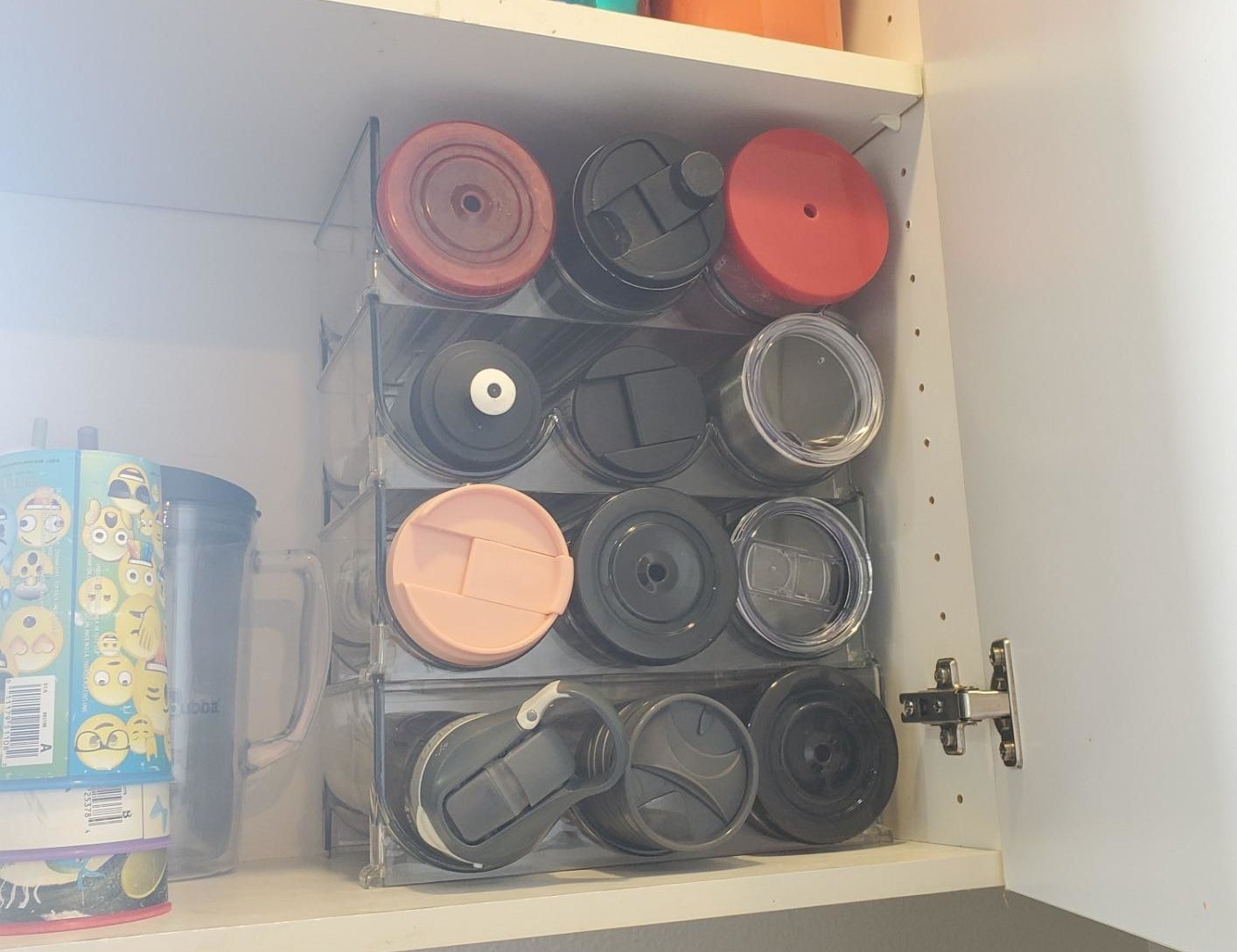 reviewer photo showing their water bottles and tumblers perfectly organized, maximizing space in their cupboards with the organizers 