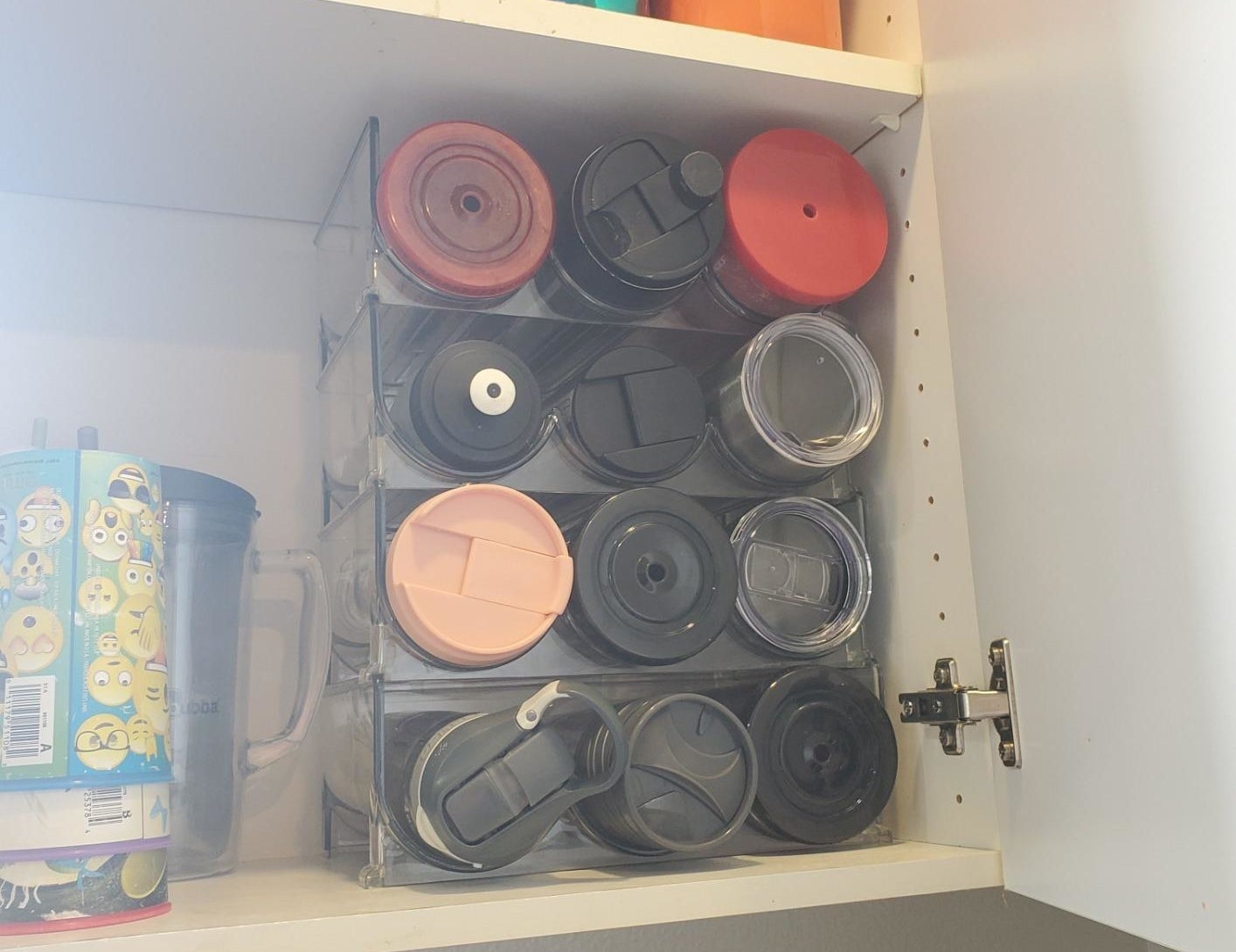 reviewer photo showing their water bottles and tumblers perfectly organized, maximizing space in their cupboards with the organizers