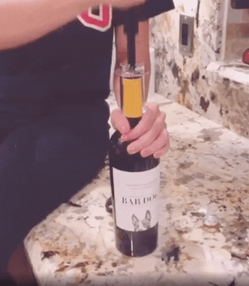 reviewer uses air pressure bottle opener to open wine