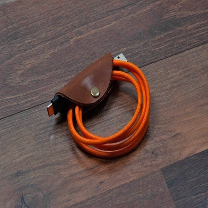 A leather taco-shaped clip holding a small cable 